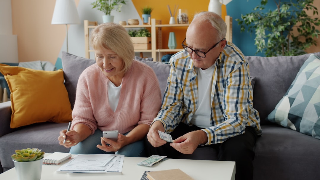 Senior man and woman are counting money looking through bills busy with finance on couch at home. Payments, family life and apartment concept.