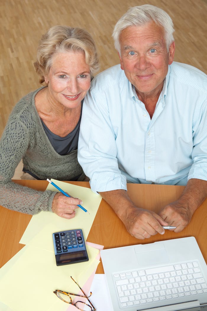 Happy senior couple using a laptop and calculator for financial planning.